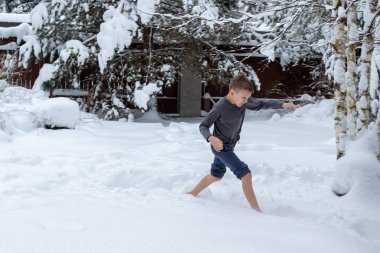 Teen barefoot runs in the snow. Winter day. Body hardening. clipart