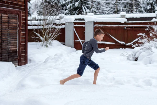 Подросток босиком бегает по снегу. Зимний день. Затвердевание тела. Затвердевание - Зимнее веселье. Здоровый образ жизни . — стоковое фото