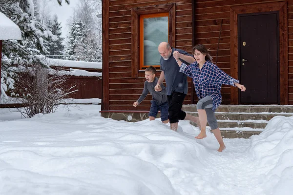 Papá, hija e hijo están descalzos corriendo en la nieve. Día de invierno. Emociones brillantes. Estilo de vida saludable. Endurecimiento corporal . —  Fotos de Stock