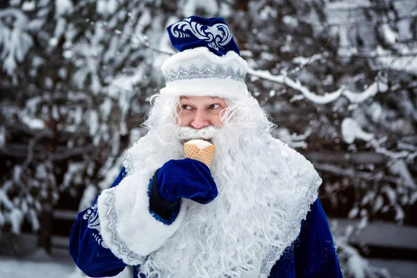 Father Frost is eating ice cream. Funny shot. Russian Christmas character Ded Moroz. Winter, December.