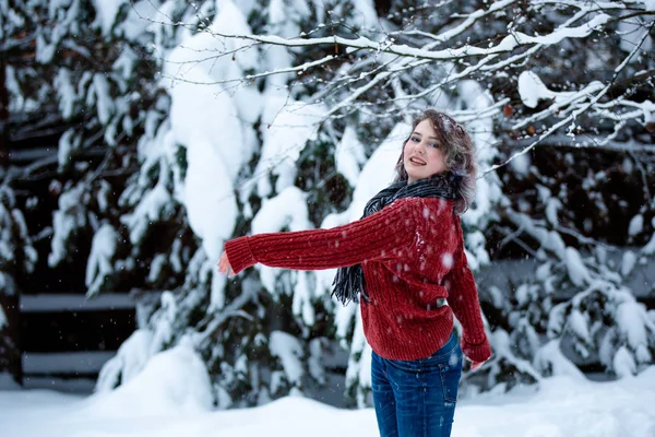 Uma linda garota de aparência caucasiana em uma camisola borgonha joga neve. Jogos de exterior. Dia de inverno — Fotografia de Stock