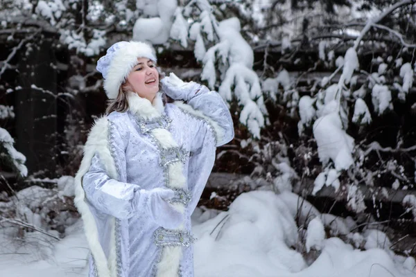 一个打扮成白雪公主的女孩在雪树的背景上扔雪球。 圣诞节和新年，冬天. — 图库照片