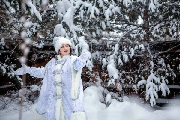 一个打扮成白雪公主的女孩在雪树的背景上扔雪球。 圣诞节和新年，冬天. — 图库照片