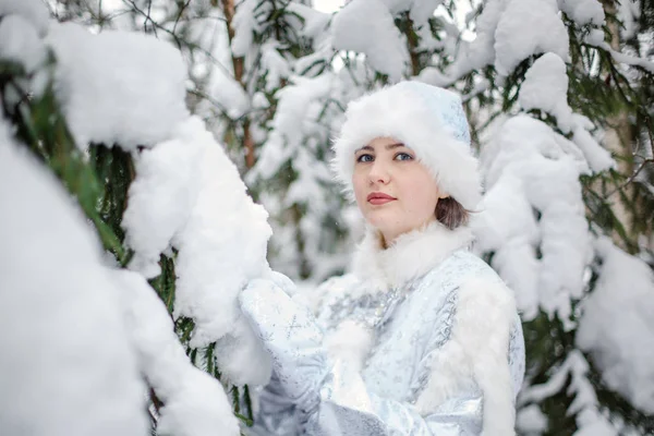 Karlı ağaçların arkasında, ormandaki Kar Kızı kostümlü kız. Kış günü. Yeni Yıl Arifesi. — Stok fotoğraf