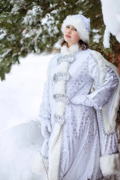 穿着雪姑娘服装的女孩在森林里的雪树下。 冬日 除夕夜. — 图库照片