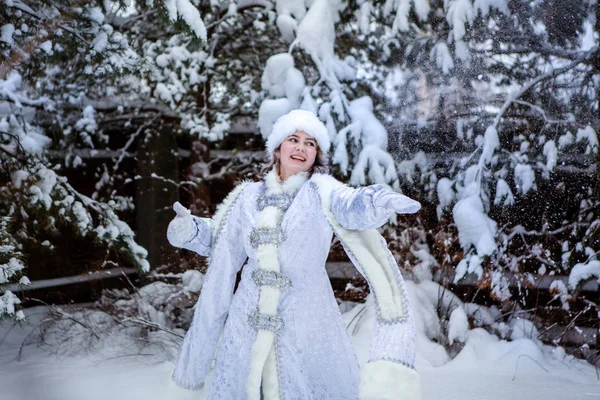 一个打扮成白雪公主的女孩在雪树的背景上扔雪球。 圣诞节和新年，冬天. — 图库照片