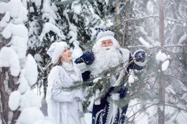 Peder Frost bir çanta dolusu hediyeyle ve ormanda bir Kar Kızıyla.