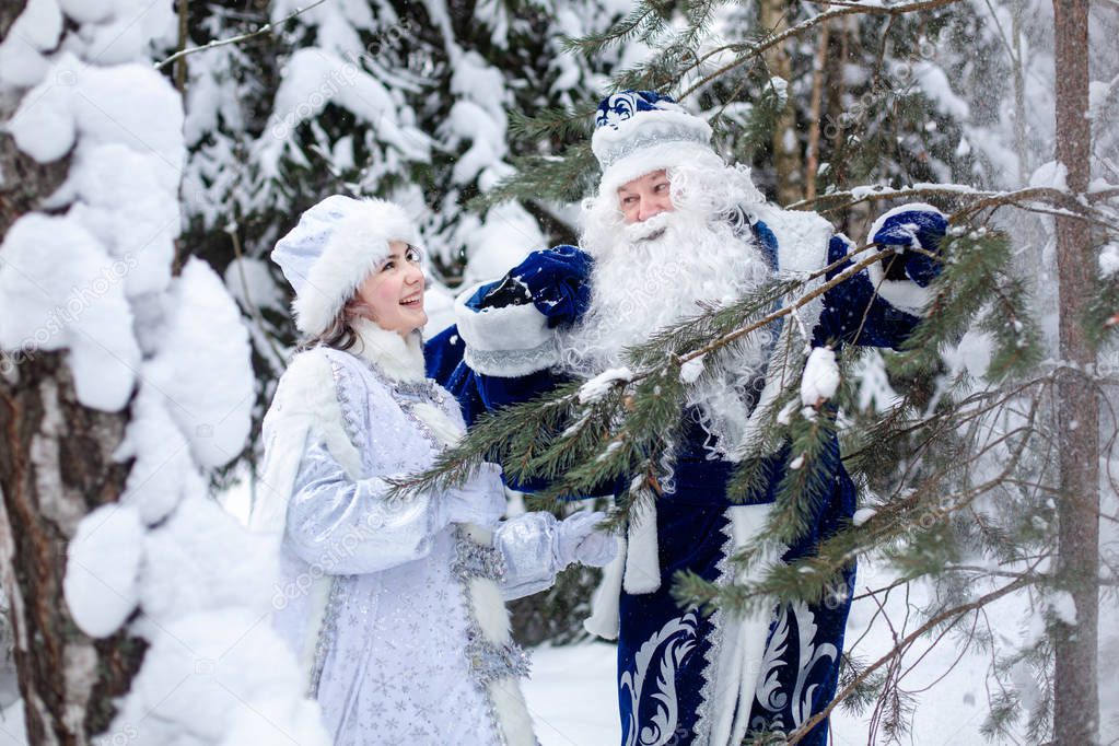 Father Frost with a bag of gifts and a Snow Maiden in the forest