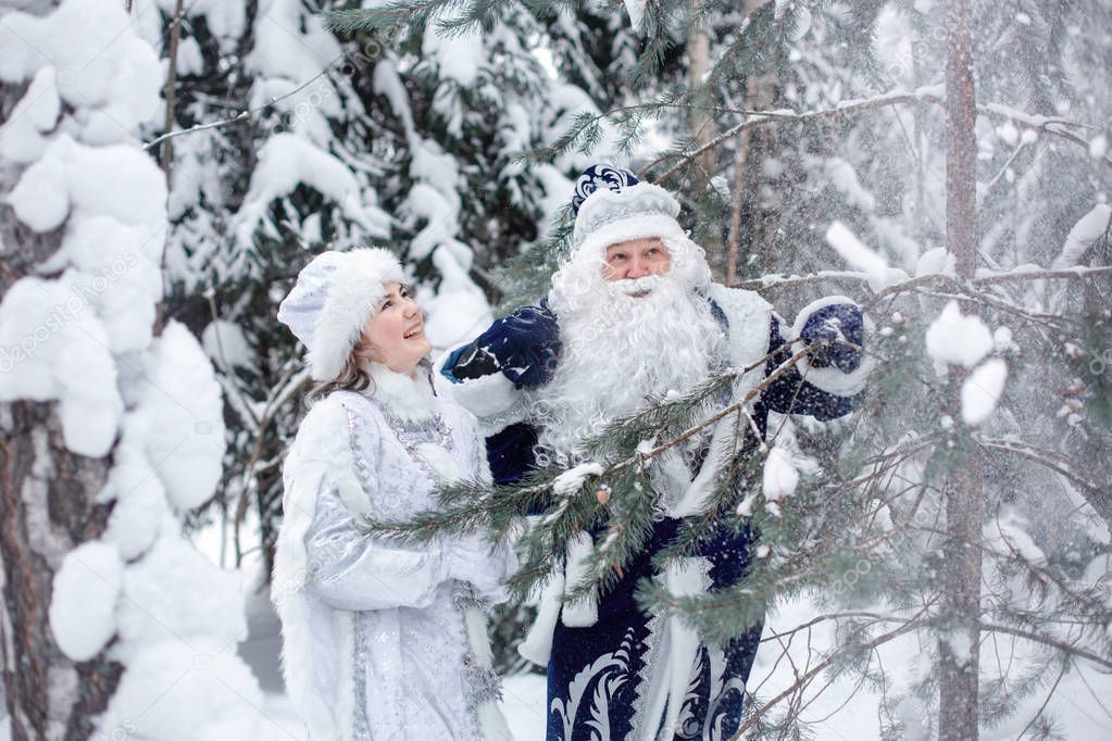 Father Frost with a bag of gifts and a Snow Maiden in the forest
