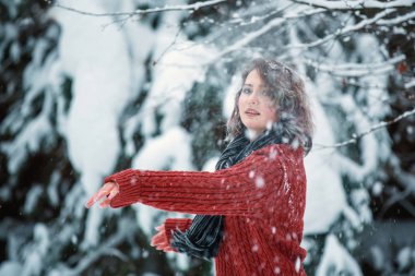 Kafkas görünümlü, bordo süveter giyen güzel bir kız kar fırlatıyor. Açık hava oyunları. Kış günü.