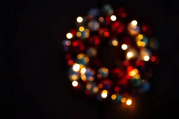 Bokeh en un círculo sobre un fondo oscuro. Corona de Navidad borrosa. Luces amarillas y rojas sobre fondo negro . —  Fotos de Stock