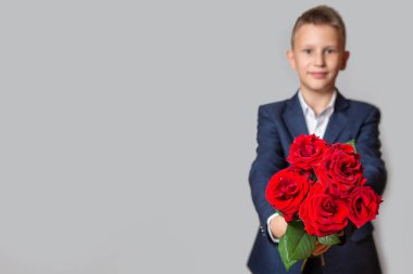 Mavi takım elbiseli beyaz bir çocuk elinde bir buket... 