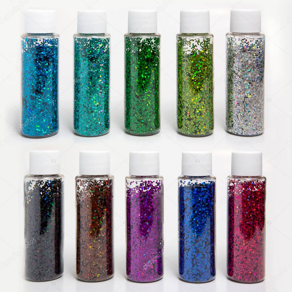 Multicolored sparkles in transparent jars on a white background. Set of 10 colors. Sparkles for slime. Holiday concept. Children goods