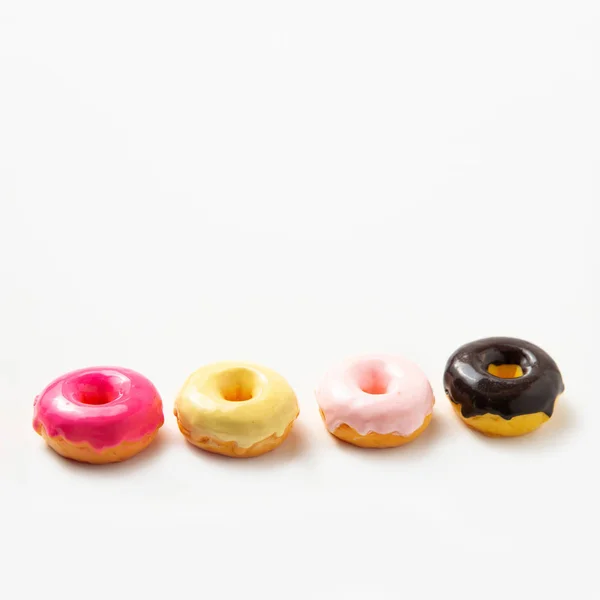 Mehrere bunte Donuts mit Schokoladenglasur auf weißem Hintergrund. Kopierraum. Dessert. Kalorienreiche Lebensmittel. — Stockfoto