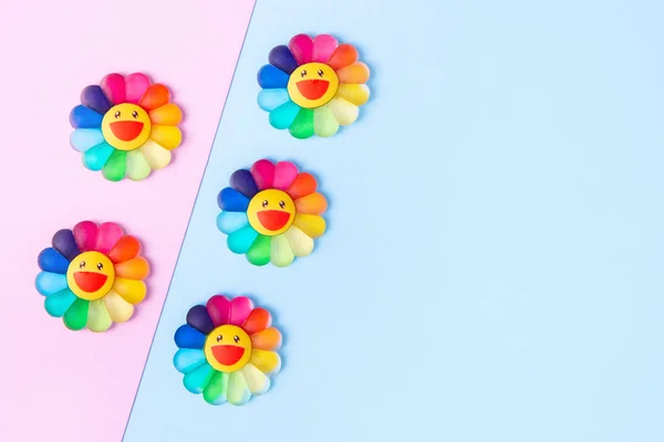 Flores de juguete con pétalos de colores arcoíris sobre un fondo rosa y azul. Mes del Orgullo. Tarjeta de felicitación, espacio para copiar . —  Fotos de Stock