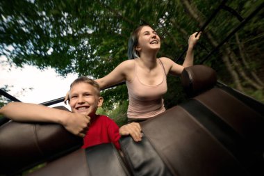 Erkek ve kız kardeş arabada neşeyle araba sürerler. Kahkaha ve neşe. Güneşli yaz günü.