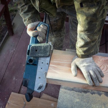 Öğütücüyle katılan birinin elleri. Uçan talaşlar, ahşap tahta. Bir profesyonelin işi. Ahşap.