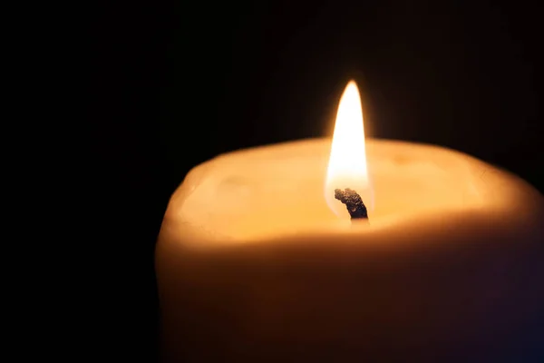 Burning candle on a dark background. Close-up, copy space.