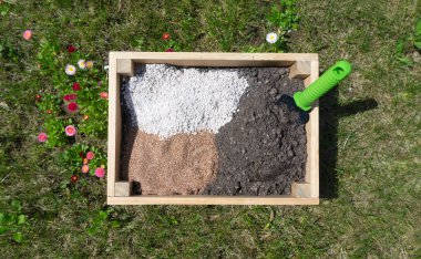 Toprak bileşenleri, biyolojik gübreler, toprak katkı maddeleri ve sebze yetiştirmek için toprak karışımının hazırlanması için geliştirmeler. Biyolojik humus, vermikülit, agroperlit, çimenlikteki tahta bir kutuda gübre.