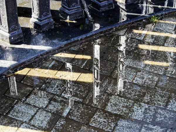 水に覆われた舗装石と水に反射される金属製のフェンス — ストック写真