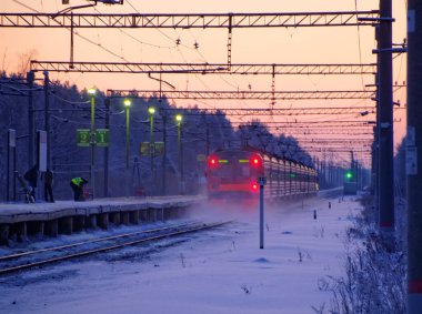 Yerel bir tren sabah erken saatlerde güneşin doğuşuyla banliyö platformundan ayrılıyor.