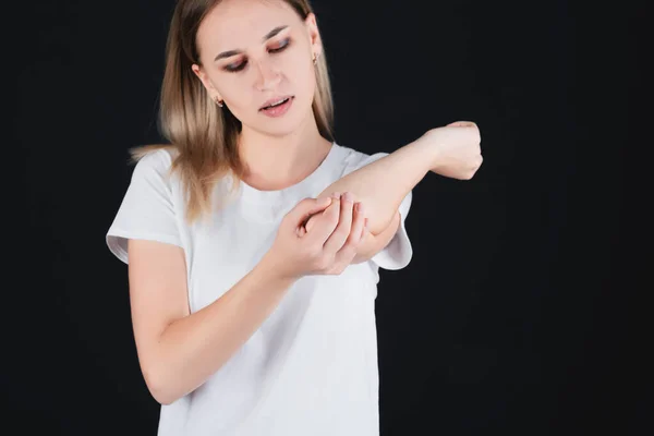 Emotional portrait of a girl holding on to a bruised elbow, experiencing pain. — Stock Photo, Image