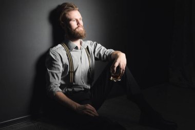 Elinde bir bardak alkol olan üzgün, yakışıklı bir gencin portresi..