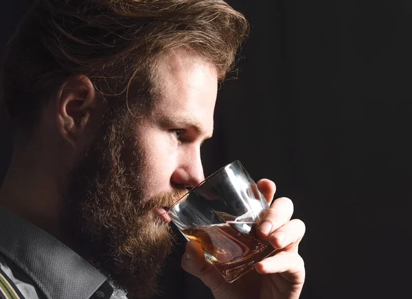 Retrato de um jovem bonito com barba bebendo álcool de um copo . — Fotografia de Stock