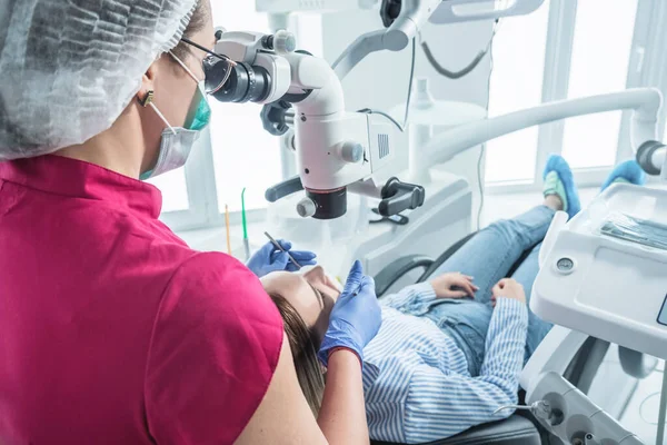 Diş hekimi, dişçi ofisinde mikroskopla hastayı muayene eder. — Stok fotoğraf