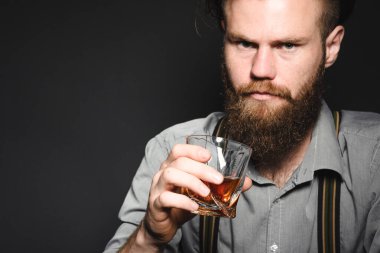 Sakallı ve bardaktan alkol içen yakışıklı bir gencin portresi..
