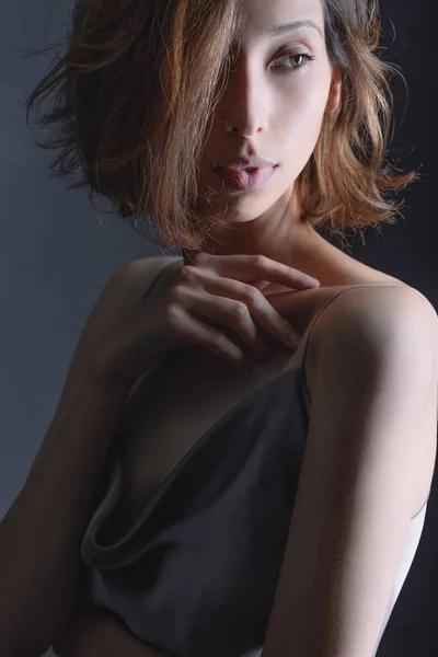 Retrato de uma menina bonita e sensual em um fundo cinza em um vestido cinza. Conceito de cuidados com a pele e juventude — Fotografia de Stock