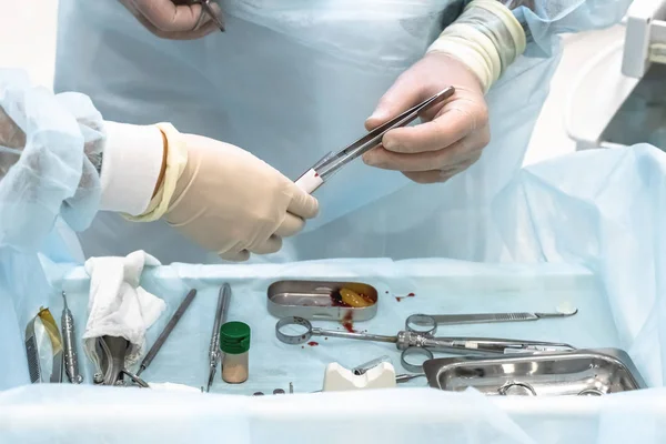 Close-up das mãos de um cirurgião dentista sobre a implantação, com instrumento dentário e modelo cirúrgico — Fotografia de Stock