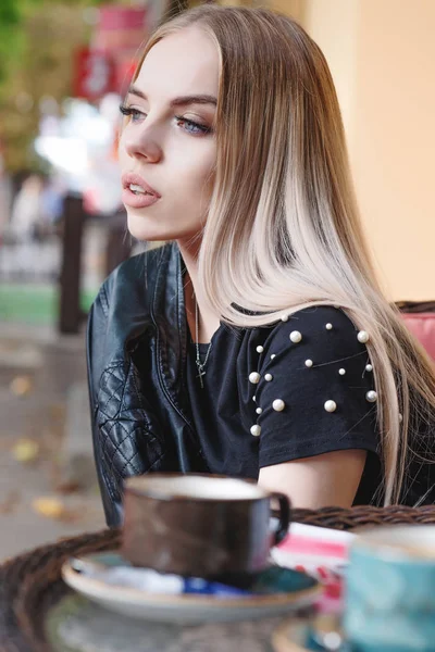 Gyönyörű gondolkodó lány ül egy kávézóban egy csésze kávét, és úgy néz ki, a távolba — Stock Fotó