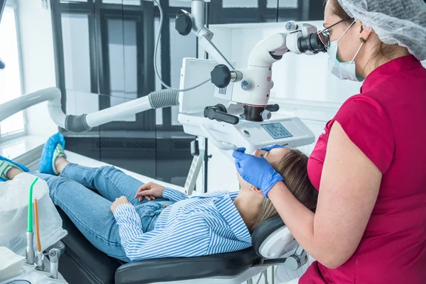 El dentista examina al paciente con un microscopio en el consultorio del dentista — Foto de Stock