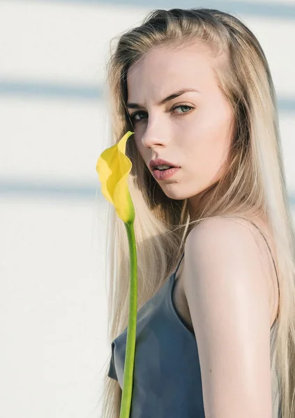 Stylová, krásná blondýnka s květinou v rukou, na pozadí geometrického vzoru — Stock fotografie