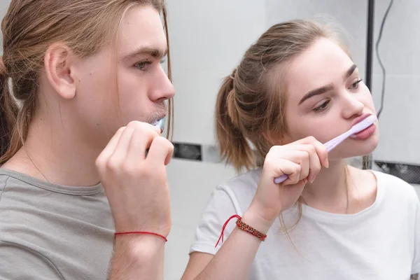 Um jovem casal escova os dentes no banheiro no início da manhã — Fotografia de Stock