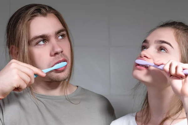 Um jovem casal escova os dentes no banheiro no início da manhã — Fotografia de Stock