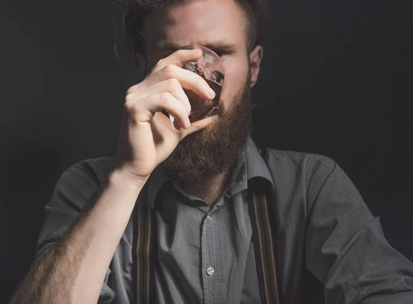 Portrait of a pensive handsome young man, with a glass of alcohol in his hands. — Stock Photo, Image