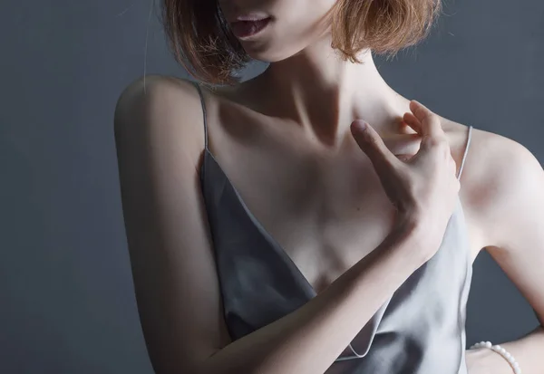Retrato de uma menina bonita e sensual em um fundo cinza em um vestido cinza. Conceito de cuidados com a pele e juventude — Fotografia de Stock