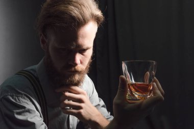 Elinde bir bardak alkolle dalgın ve yakışıklı bir gencin portresi..