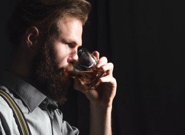 Elinde bir bardak alkolle dalgın ve yakışıklı bir gencin portresi..