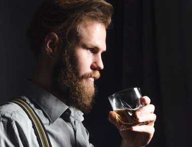 Elinde bir bardak alkolle dalgın ve yakışıklı bir gencin portresi..