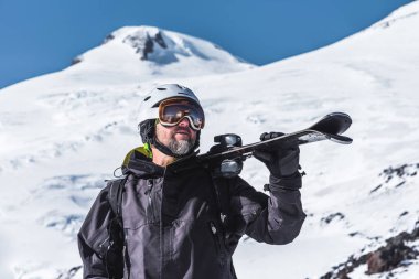 Kayaklı bir adam dağlarda dikilip manzaranın tadını çıkarıyor. Yokuş aşağı kayak, aşırı rahatlama.