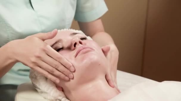Gesundheit, Schönheit, Kur- und Entspannungskonzept - schöne Frau im Wellness-Salon bekommt Gesichtsbehandlung — Stockvideo