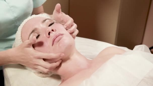 Salud, belleza, resort y concepto de relajación - hermosa mujer en el salón de spa recibiendo tratamiento facial — Vídeo de stock