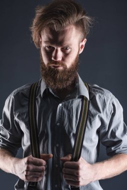 Stüdyoda siyah bir arka planda poz veren sakallı, genç, yakışıklı bir adam..