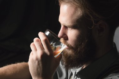 Elinde bir bardak alkolle dalgın ve yakışıklı bir gencin portresi..