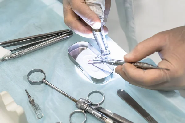 Крупный план рук стоматолога-хирурга на имплантации, с зубным инструментом и хирургическим шаблоном — стоковое фото