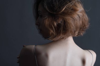 Gri bir arka planda gri elbiseli güzel, şehvetli bir kızın portresi. Gençlik ve cilt bakımı kavramı