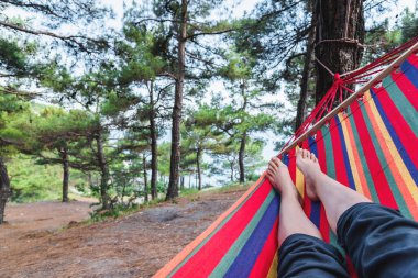 Ormandaki bir hamağın ayaklarının birinci şahıs görüntüsü. Açık hava eğlencesi konsepti